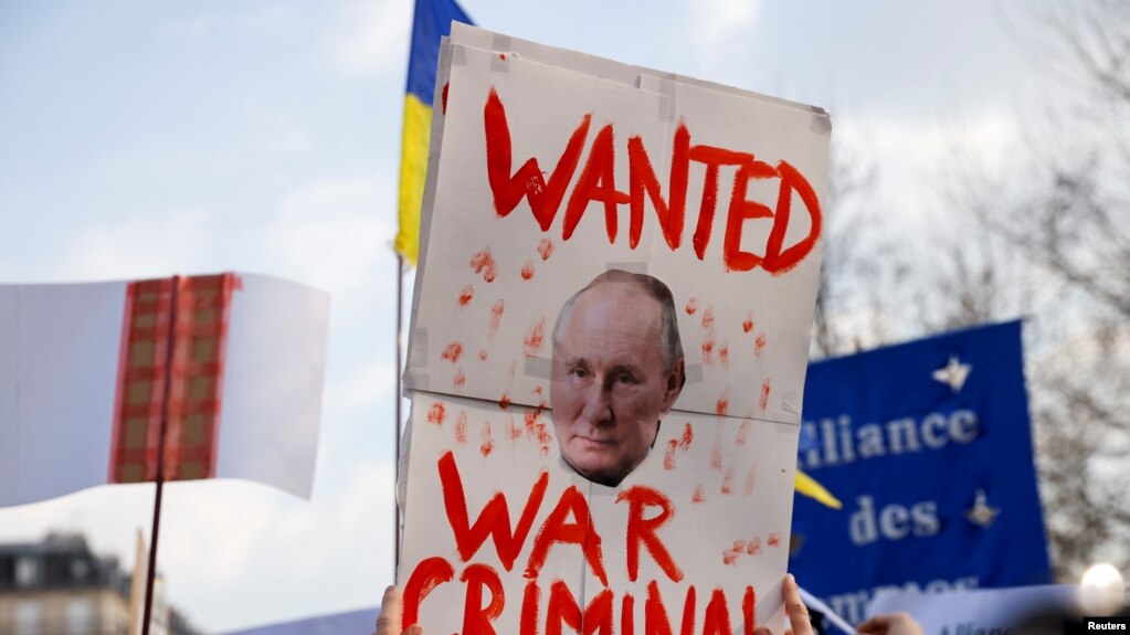 Una persona sostiene un cartel con una imagen del presidente ruso Vladimir Putin durante una protesta en el Reino Unido.