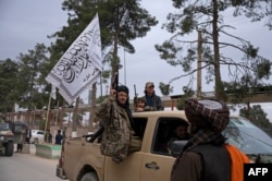 FILE - Taliban fighters take part in a military street parade in Maymana, capital of Faryab province, Jan. 16, 2022.