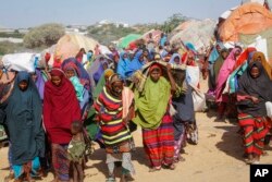 FILE - Somalis who fled drought-stricken areas carry their belongings as they arrive at a makeshift camp on the outskirts of the capital Mogadishu, Somalia, Feb. 4, 2022.