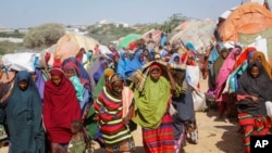 Somalis who fled drought-stricken areas carry their belongings as they arrive at a makeshift camp on the outskirts of the capital Mogadishu, Somalia Friday, Feb. 4, 2022.