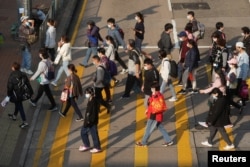 People wearing face masks cross a street during the COVID-19 outbreak, in Hong Kong, China, Feb. 15, 2022.