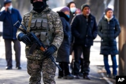 FILE - Relatives of some of those arrested after anti-government protests gather near a police station, hoping to learn their fate, while a Kazakhstan soldier patrols a street, in Almaty, Kazakhstan, Jan. 14, 2022.