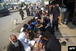 FILE - A volunteer serves food to people in need along a street in Karachi, Jan. 10, 2022,