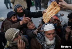 FILE - People reach out to receive bread, in Kabul, Afghanistan, Jan. 31, 2022.