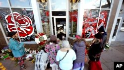 FILE - Mourners gather outside a tattoo parlor, one of the scenes of a shooting spree by Lyndon McCleod, in Denver on on Dec. 28, 2021. 