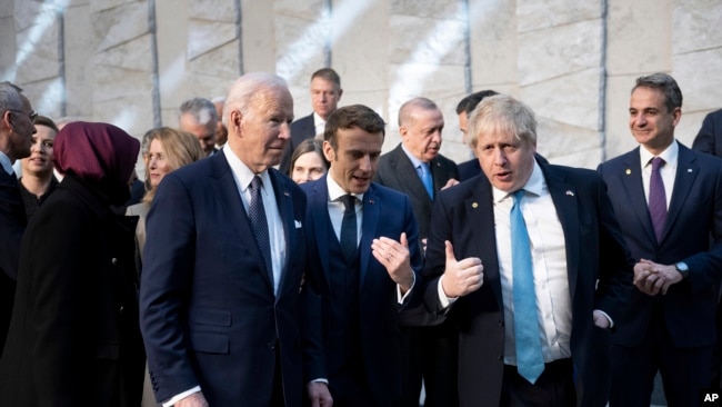 President Joe Biden, left, talks with French President Emmanuel Macron and Briitish Prime Minister Boris Johnson, right, as they arrive at NATO Headquarters in Brussels, Thursday, March 24, 2022. (Brendan Smialowski, Pool via AP)