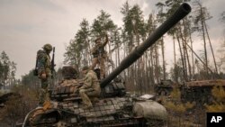 Lính Ukraine xem xét xe tăng Nga bị tiêu diệt ở ngoại ô Kyiv, Ukraine, 31/3/2022. 