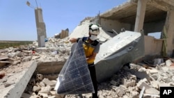 FILE - A civil defense worker inspects a damaged house after shelling hit the town of Ibleen, a village in southern Idlib province, Syria, July 3, 2021.
