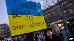 FILE - A protester holds a sign calling on NATO to establish a no-fly zone over Ukraine, during a rally in Paris, France, Feb. 26, 2022.

