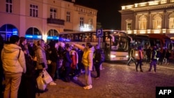 People wait to board buses taking them to Warsaw outside the train station in Przemysl, which became a main transfer hub for refugees fleeing Russia's invasion of Ukraine, March 12, 2022.