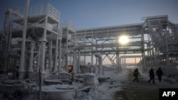 FILE - People walk through the Utrenneye field, the resource base for Russia's Arctic LNG 2 project, located in the Gydan Peninsula on the Kara Sea shore line in the Arctic Circle, some 2,500 kilometers from Moscow, Nov. 30, 2021.