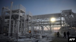 FILE - People walk through the Utrenneye field, the resource base for Novatek's Arctic LNG 2 project, located in the Gydan Peninsula on the Kara Sea shore line in the Arctic circle, some 2,500 km from Moscow, Nov. 30, 2021.