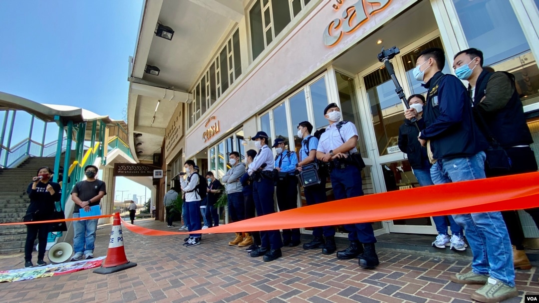 香港警方在距離北京駐港機構中聯辦超過100米的一間餐廳門外，拉起封鎖線設立”示威區”，禁止兩名社民連成員靠近中聯辦示威。(美國之音湯惠芸)