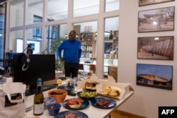 Burkinabe architect Diebedo Francis Kere is seen during a celebration next to pictures of some of his projects on the wall in his office in Berlin, on March 15, 2022, after being awarded the 2022 Pritzker Architecture Prize.
