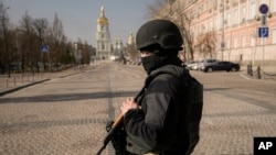 A Ukrainian serviceman stands at a checkpoint in Kyiv, Ukraine, March 24, 2022. Ukraine President Volodymr Zelenskyy called on people worldwide to gather in public Thursday to show support for his embattled country.