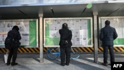 FILE - A man, center, reads the Chinese state-run newspaper with coverage of the conflict between Russia and Ukraine, on a street in Beijing, Feb. 24, 2022.