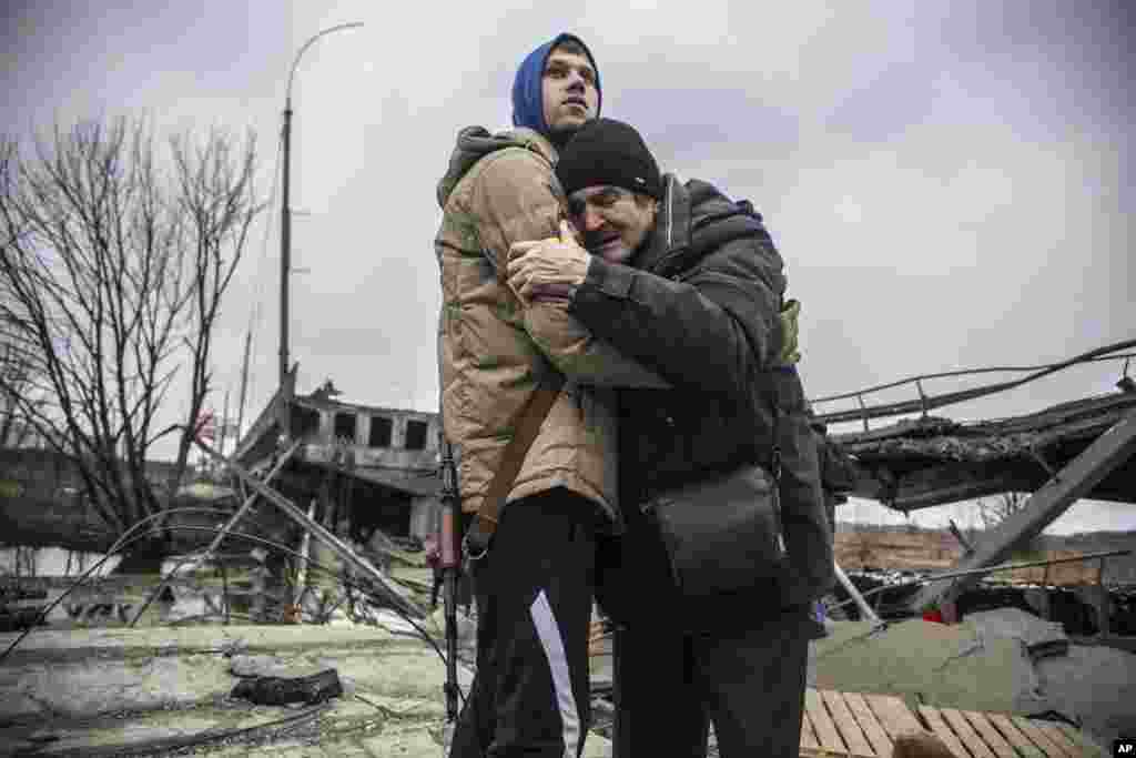A Ukrainian Territorial Defense Forces member hugs a resident who leaves his home town following Russian artillery shelling in Irpin, on the outskirts of Kyiv, March 9, 2022. (AP Photo/Oleksandr Ratushniak)