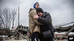 A Ukrainian Territorial Defense Forces member hugs a resident who leaves his home town following Russian artillery shelling in Irpin, on the outskirts of Kyiv, March 9, 2022. (AP Photo/Oleksandr Ratushniak)