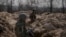 Ukrainian servicemen stand in trenches at a position north of the capital Kyiv, Ukraine, March 29, 2022. 