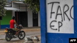 FILE - A man in motorcycle passes by a written wall that reads "FARC EP" in Arauquita, Colombia, on the border with Venezuela, on January 23, 2022. (Photo by Juan BARRETO / AFP)