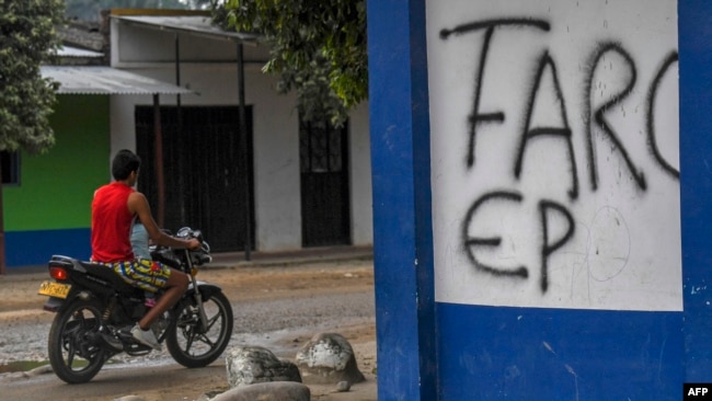 FILE - A man in motorcycle passes by a written wall that reads "FARC EP" in Arauquita, Colombia, on the border with Venezuela, on January 23, 2022. (Photo by Juan BARRETO / AFP)