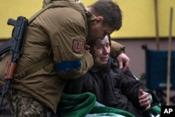 A soldier comforts Larysa Kolesnyk, 82, after being evacuated from Irpin, on the outskirts of Kyiv, Ukraine, March 30, 2022.