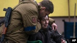 A soldier comforts Larysa Kolesnyk, 82, after being evacuated from Irpin, on the outskirts of Kyiv, Ukraine, March 30, 2022.