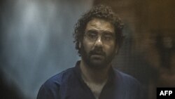 FILE: Egyptian activist and blogger Alaa Abdel Fattah looks on from the defendant's cage during his trial for insulting the judiciary alongside 25 other defendants, in Cairo. Taken May 23, 201