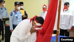 Satu dari delapan narapidana terorisme di Sumut sedang mencium bendera Merah Putih, Rabu 9 Maret 2022. (Courtesy: Humas Kemenkumham Sumut).