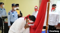 Satu dari delapan narapidana terorisme di Sumut sedang mencium bendera Merah Putih, Rabu 9 Maret 2022. (Courtesy: Humas Kemenkumham Sumut).