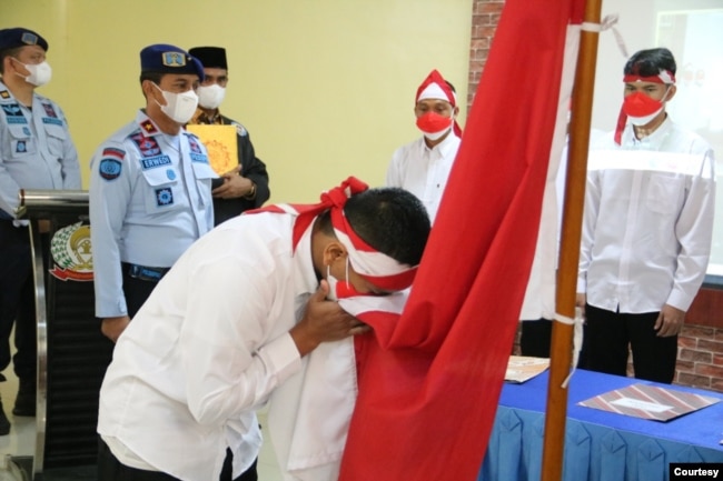 Satu dari delapan narapidana terorisme di Sumut sedang mencium bendera Merah Putih, Rabu 9 Maret 2022. (Courtesy: Humas Kemenkumham Sumut).