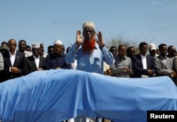 Relatives and Somali government officials pray near the slain body of Amina Mohamed Abdi, a vocal critic of the government, who was killed in a suicide explosion in Beledweyne, at the Adan Abdulle International Airport international in Mogadishu, Somalia, March 24, 2022.