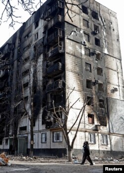 Local residents walk past an apartment building damaged during Ukraine-Russia conflict in the besieged southern port city of Mariupol, Ukraine March 31, 2022.