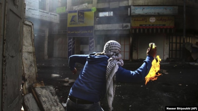 FILE - A Palestinian protester throws a Molotov cocktail towards Israeli soldiers during conflicts in the West Bank city of Hebron, April 3, 2013. (AP Photo/Nasser Shiyoukhi, File)