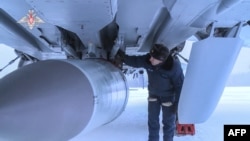 FILE - This handout video grab released by the Russian Defense Ministry on Feb. 19, 2022, shows an airman examining a MiG-31K fighter jet of the Russian air force carrying a Kinzhal hypersonic missile at an undisclosed location in Russia.