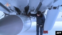 FILE - This handout video grab released by the Russian Defense Ministry on Feb. 19, 2022, shows an airman examining MiG-31K fighter of the Russian air force carrying a Kinzhal hypersonic cruise missile at an undisclosed location in Russia.