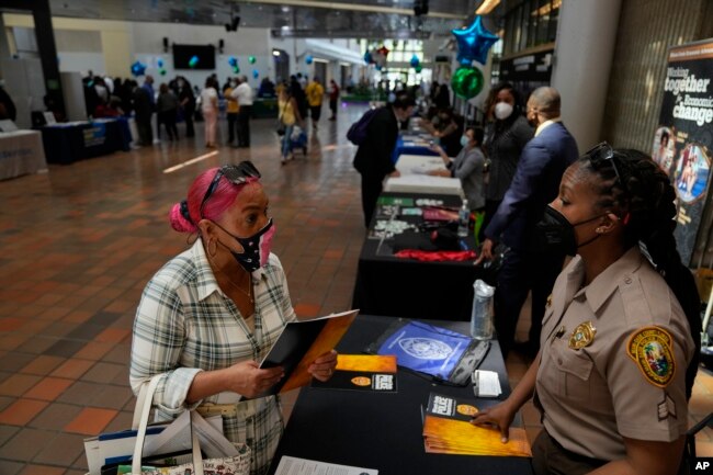 Seorang pencari kerja (kiri), berbicara dengan Sersan. Jannene Howard-Brown dari Departemen Kepolisian Miami-Dade saat dia bertanya tentang peluang administratif dengan departemen sambil mempertimbangkan untuk merubah karirnya di pameran pekerjaan Miami-Dade County, pusat kota Miami, Rabu, 23 Februari 2022.(AP/Rebecca Blackwell)