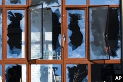 A man appears through shattered windows of a building after a shelling in Odesa, Ukraine, March 21, 2022.