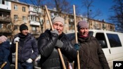 A woman cries before starting to clean the site where a bombing damaged residential buildings in Kyiv, Ukraine, March 18, 2022. Russian forces pressed their assault on Ukrainian cities Friday, with new missile strikes and shelling on the edges of Kyiv and