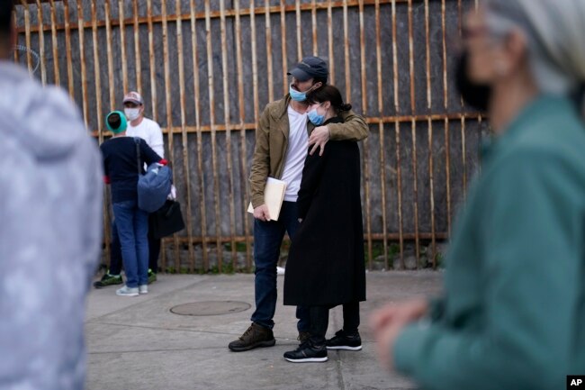 FILE - A woman from Ukraine stands at the border with her fiance from the United States as she waits to ask for asylum, in Tijuana, Mexico, March 10, 2022.