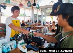 Senator Ruslan, warga Rusia, mencoba menggunakan kartu ATM Rusia miliknya untuk membayar makan siang di Bali. (Foto: REUTERS/Sultan Anshori)