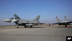 Vojni oficir prolazi između bugarskog MiG-29 i španskog aviona Eurofighter EF-2000 Typhoon II i MiG-29, u Graf Ignatievu, četvrtak, 17. februara 2022. 