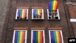 FILE - Rainbow flags cover windows in Soho as members of the lesbian, gay, bisexual and transgender (LGBT) community hold the annual Pride Parade in London on July 6, 2019.