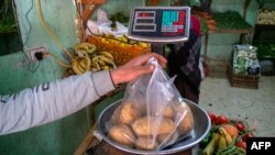 FILE: An Egyptian man weighs potatoes in a shop at a market in Cairo, on March 17, 2022. - Soaring prices have bitten into the purchasing power of Egyptian consumers.