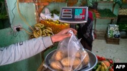 FILE: An Egyptian man weighs potatoes in a shop at a market in Cairo, on March 17, 2022.