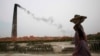 FILE - Smoke emits from chimney as a Bangladeshi female worker carries clay at a brick field at Amin Bazar, outskirts of Dhaka, Bangladesh, Thursday, May 14, 2009.