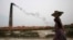 FILE - Smoke emits from chimney as a Bangladeshi female worker carries clay at a brick field at Amin Bazar, outskirts of Dhaka, Bangladesh, Thursday, May 14, 2009.