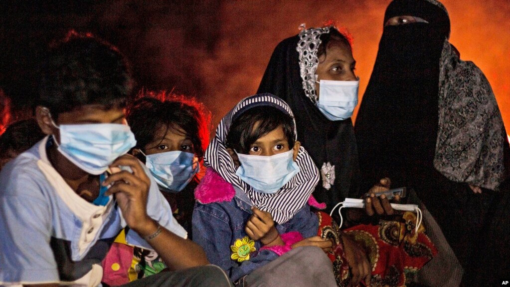 Ethnic Rohingya women and children sit by a fire on a beach after their boat was stranded on Idaman Island in East Aceh, Indonesia, late Friday, June 4, 2021, after leaving a refugee camp in Bangladesh, officials said. (AP Photo/Zik Maulana)