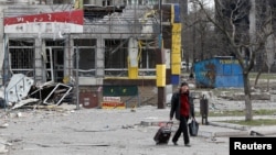 A man walks near a building damaged in the course of the Ukraine-Russia conflict in the southern port city of Mariupol, Ukraine, April 1, 2022.