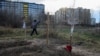 A boy walks past graves with bodies of civilians, who according to local residents were killed by Russian soldiers, in Bucha, in Kyiv region, Ukraine April 4, 2022.